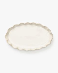 a white platter with scalloped edges on a white background, it looks like an oval dish