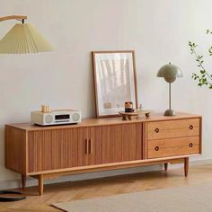 a living room with a wooden cabinet, lamp and pictures on the wall above it