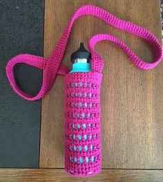 a pink and blue water bottle sitting on top of a wooden table next to a bag