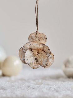 an ornament hanging from a string on top of a white surface with eggs in the background