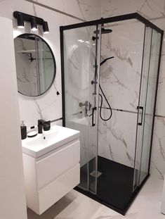 a bathroom with a sink, mirror and shower stall in white marbled tiles on the walls