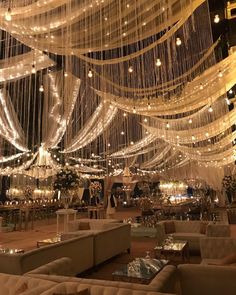 a room filled with lots of white couches and chandeliers hanging from the ceiling