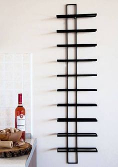 a wine bottle is sitting on a counter next to a wall sculpture with black bars