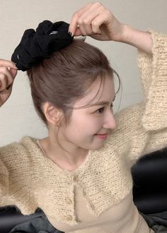 a woman with a black bow in her hair is sitting down and combing her hair