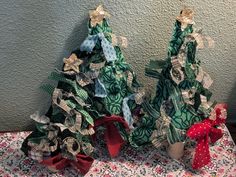 two small christmas trees sitting on top of a table covered in bows and ribbons, next to each other