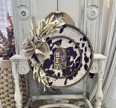 a chair with a cow print plate on top of it next to a basket filled with flowers