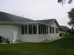 a white house sitting on top of a lush green field next to a tree and grass covered yard