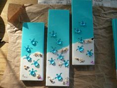 three blue boxes with sea shells and seashells on them sitting on brown paper