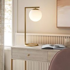 a desk with a lamp on it and a book sitting on top of the table