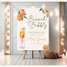 a wedding sign with oranges on it next to a bag and some string lights