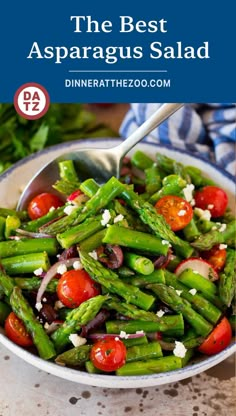 a bowl filled with asparagus, tomatoes and other veggies on top of a table