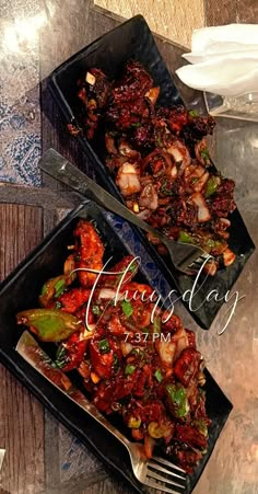 two black trays filled with food on top of a table