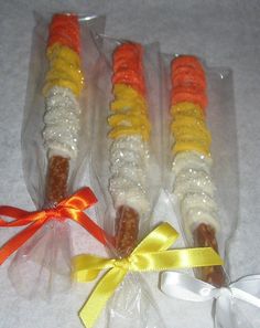 three candy sticks wrapped in plastic and tied with a yellow ribbon on a white surface