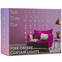 pink ombre curtain lights in front of a purple couch with white pillows on it