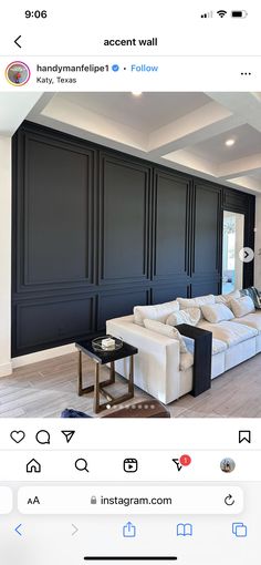 a living room with black paneling and white couches in the middle of it