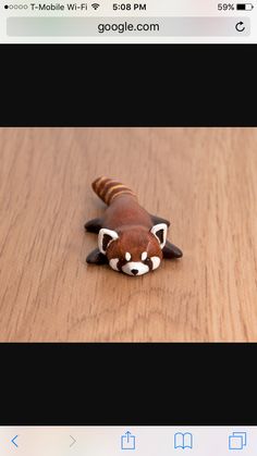 a small toy racoon laying on top of a wooden table