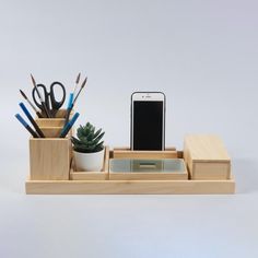 a cell phone, pen and pencil holder on a white surface with succulents