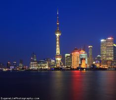 the city skyline is lit up at night with lights reflecting in the water and skyscrapers