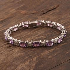 Rhodium plated sterling silver forms a gleaming circle around the wrist in this tennis bracelet from Bhavesh in India. Basket-style settings hold over 19 carats of brilliant faceted amethyst, while X shapes in between are studded with sparkly cubic zirconia. The slender link bracelet is a gem-lover's dream. Anniversary Amethyst Gemstone Tennis Bracelet, Luxury Purple Sterling Silver Bracelets, Silver Amethyst Bracelets For Anniversary, Purple Jewelry With Jubilee Bracelet For Anniversary, Elegant Silver Tennis Bracelet With Amethyst, Sterling Silver Amethyst Bracelet For Anniversary, Elegant Silver Amethyst Tennis Bracelet, Elegant Silver Tennis Bracelet, Silver Amethyst Tennis Bracelet With Gemstones