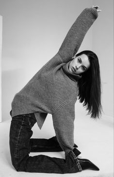 a woman is sitting on the floor with her arms in the air and looking at the camera