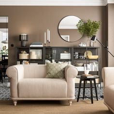 a living room filled with furniture and a round mirror on the wall over a coffee table