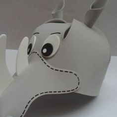 an elephant made out of white paper with black eyes and nose on it's head