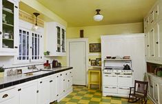 a kitchen with white cabinets and yellow checkered flooring on the walls is shown