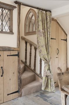 a room with wooden stairs and curtains on the windows