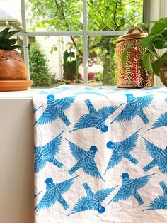 a blue and white table cloth sitting on top of a window sill next to a potted plant