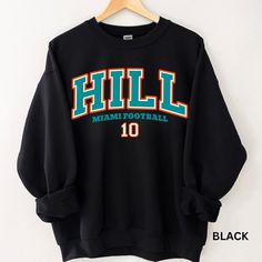 Perfect sweatshirt for Miami football and Tyreek Hill fans this season! Ideal for any situation, a unisex heavy blend crewneck sweatshirt is pure comfort. These garments are made from polyester and cotton. This combination helps designs come out looking fresh and beautiful. The collar is ribbed knit, so it retains its shape even after washing. There are no itchy side seams on these sweaters.  .: 50% cotton, 50% polyester .: Medium-heavy fabric (8.0 oz/yd² (271.25 g/m .: Loose fit .: Sewn-in label .: Runs true to size CARE INSTRUCTIONS: -Please wash all clothing items INSIDE OUT to preserve the design. -Please wash all clothing items on cold, and dry on Medium- low heat. -DO NOT IRON. -DO NOT TIE DYE. **Please check our color and size charts before you place your order. If you have any ques Collegiate Black Sweatshirt For Football Season, Black Football Season Sweatshirt With Team Name, Black Sweatshirt With Team Name For Football Season, Black Sweatshirt With Football Team Name, Black College Sweatshirt For Football Season, Black Fan Apparel Sweatshirt For Football Season, Pre-shrunk Crew Neck Sweatshirt For School Spirit, Collegiate Style T-shirt With Ribbed Cuffs, Black Sweatshirt For Football Season Streetwear