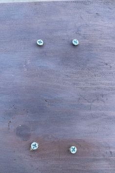 four blue buttons are on a wooden surface with holes in the middle to indicate where they came from