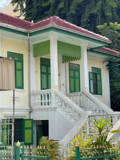 a white house with green shutters on the front and stairs leading up to it