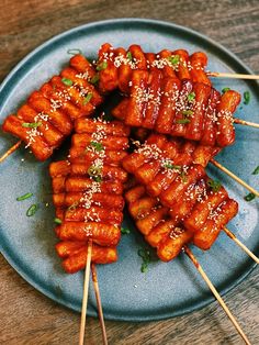 several skewered meats with sesame seeds and seasoning on a blue plate