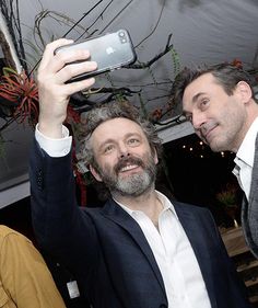 two men are taking a selfie with their cell phones in front of the camera