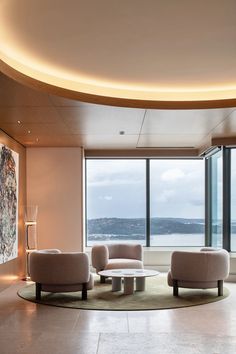 a living room with two couches and a table in front of large windows overlooking the ocean