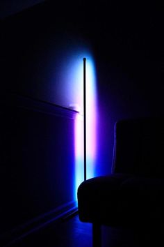 a chair sitting in the dark next to a tall pole with colored lights on it