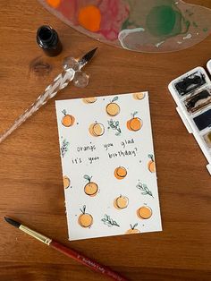 a card with oranges on it next to some watercolor paints