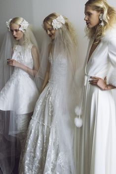 three women in white dresses and veils standing next to each other with their hands on their hips