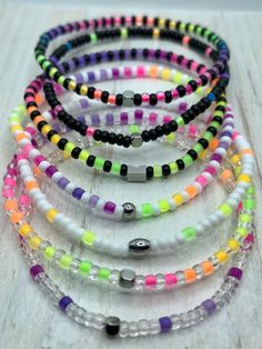 multicolored beaded stretch bracelets on white wooden background with space for text