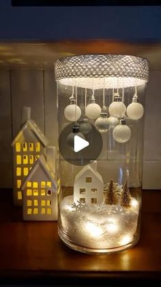 a glass jar filled with snow and christmas ornaments on top of a wooden table next to a