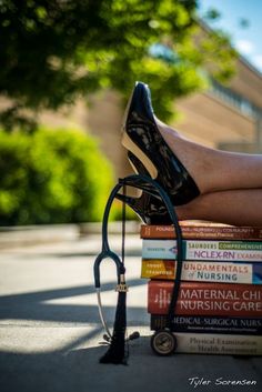 a woman's legs wearing black high heels and reading glasses on top of books