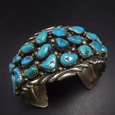 TIMOTHY LEE (NAVAJO) BLUE KINGMAN TURQUOISE STERLING SILVER CUFF BRACELET DESCRIPTION:  With breathtaking specimens of blue Kingman turquoise that cover the entire cuff, along with applied raindrops and chisel stamped accents, this bracelet will be a cherished addition to your collection of fine vintage Southwestern and Native American jewelry. MEASUREMENTS: Interior of the cuff measures 6" with an additional 1 1/4" non-adjustable gap. Total circumference:  7 1/4" Measures 2 1/2" straight across Southwestern Blue Cuff Bracelet As Gift, Western Style Blue Bangle Jewelry, Southwestern Style Blue Bangle Bracelets, Southwestern Style Blue Bangle Bracelet, Western Style Blue Cuff Bracelet Gift, Handmade Southwestern Blue Bracelets, Western Style Blue Cuff Bangle Bracelet, Adjustable Southwestern Blue Cuff Bracelet, Artisan Blue Bracelets Collectible