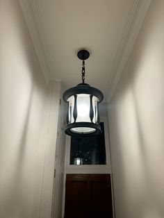 the light fixture is hanging from the ceiling above the door way in this hallway with white walls