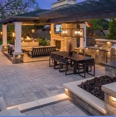 an outdoor kitchen and dining area is lit up at night with candles on the tables