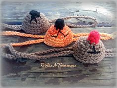 three crocheted hats with black and red pom poms are on a wooden surface