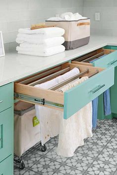 an open drawer in the middle of a kitchen with towels hanging on it's sides