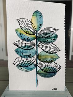 a watercolor painting of a green leaf on white paper with blue and yellow accents