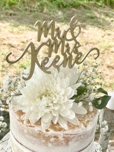 a wedding cake with white flowers and the word mr and mrs on top is shown