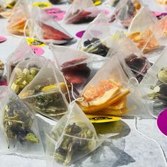 several bags filled with different types of teas on top of a white tablecloth