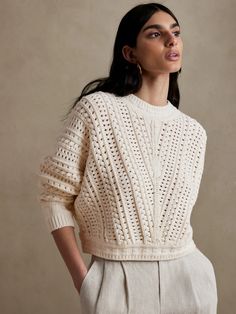 a woman is wearing a white sweater and pants